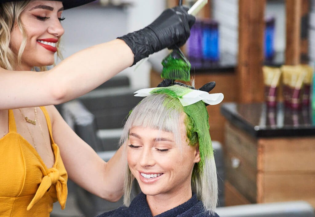 Larisa Love coloring clients hair green