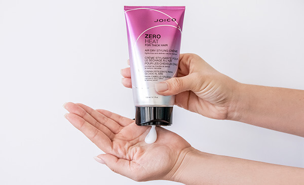 Zero-Heat-thick-hair-in-hand Hair styling product being squeezed out of bottle