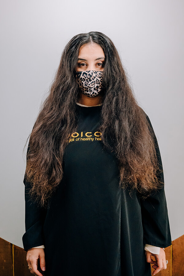 Woman with long hair and mask taking before picture of hair transformation