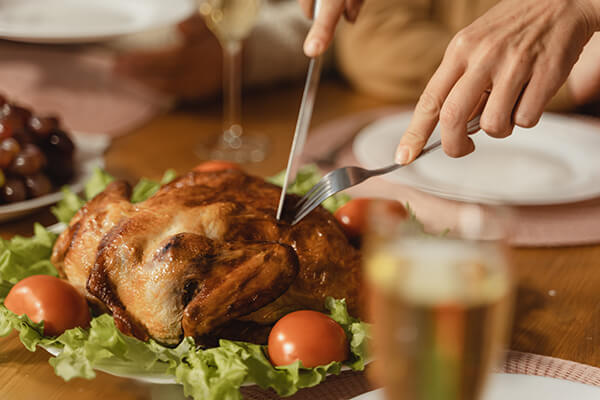thanksgiving-meal hands with knife and fork cutting into a cooked turkey