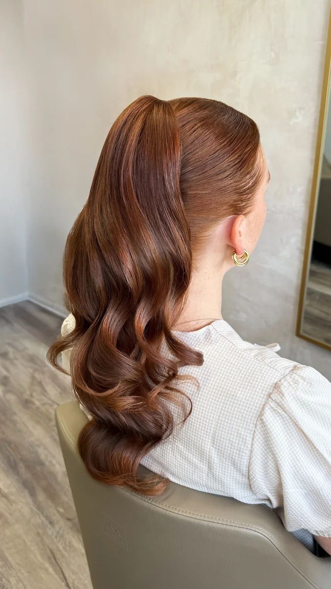Red hair woman with luscious curly ponytail close up from behind