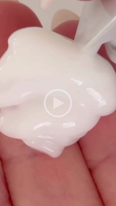 White lotion liquid on hand with play button