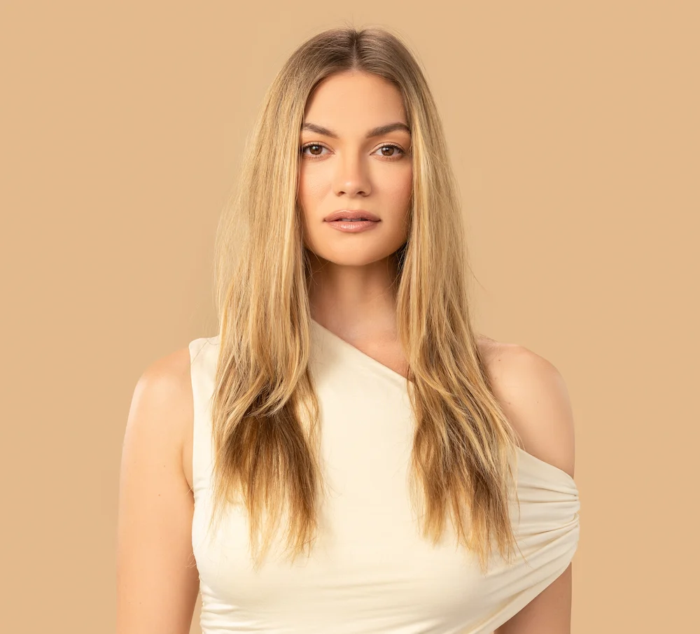 Woman with frizzy hair standing in front of tan colored background