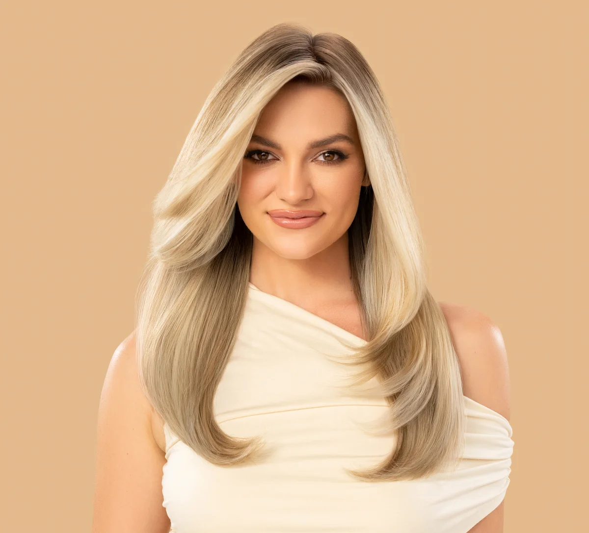Woman with nice hair smiling in front of tan colored background