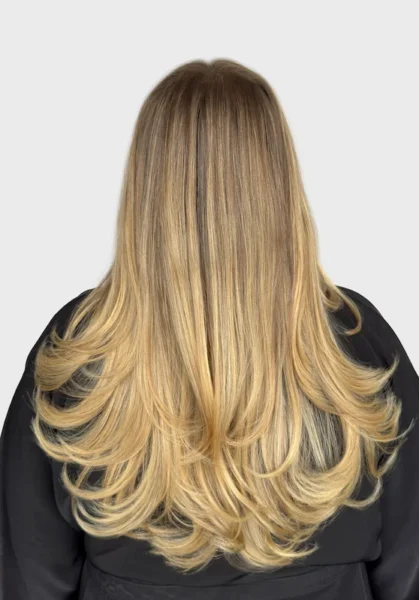 Back of woman's head showing long highlighted hair with curled tips